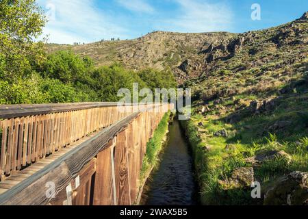 Guarda, Portugal - 10 avril 2023 : passerelles Mondego avec des canaux d'eau le long de la route et les pentes rocheuses de la montagne en arrière-plan. Banque D'Images