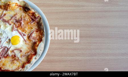 Une assiette appétissante de pizza garnie d'œufs au plat Banque D'Images