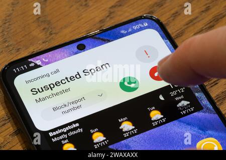 Un écran de téléphone mobile montrant un appel suspect entrant avec un doigt passant au-dessus du bouton raccrocher, Royaume-Uni. Thème : appels à froid, appels gênants Banque D'Images