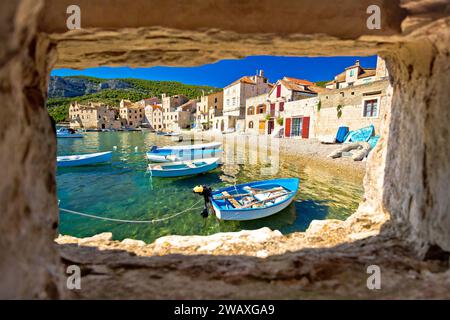 Plage pittoresque à Komiza vue sur le front de mer à travers la fenêtre en pierre, île de vis, Croatie Banque D'Images