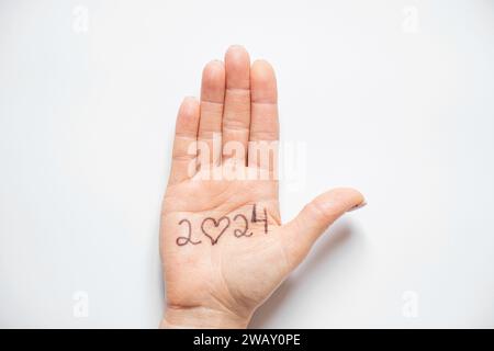 2024 et un coeur à la place de zéro est écrit sur la main d'une femme qui repose sur un fond blanc, aide et soutien dans la nouvelle année 2024, amour Banque D'Images