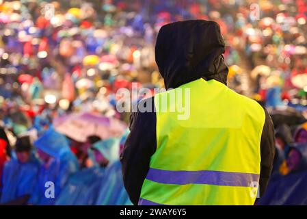 garde dans le stade rempli de gens avec le gilet phosphorescent pour contrôler les gens pendant l'événement Banque D'Images