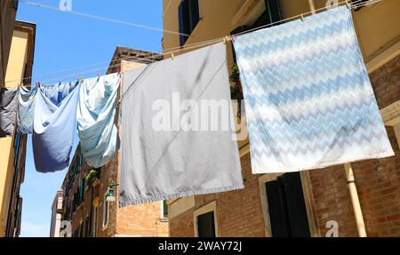 beaucoup de vêtements traînaient à sécher au soleil avec des draps et des taies d'oreiller dans une allée Banque D'Images