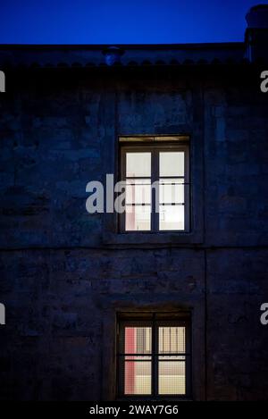 Deux fenêtres éclairées dans une maison la nuit dans une rue à Montpellier, France Banque D'Images