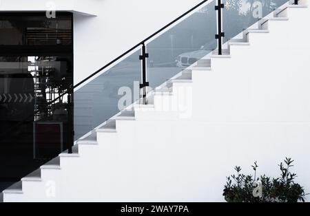 Marches blanches avec balustrade en verre. Escalier en pierre dans une maison résidentielle, bâtiment de l'industrie de la construction. Marches en béton. Vue des marches en béton et ra Banque D'Images