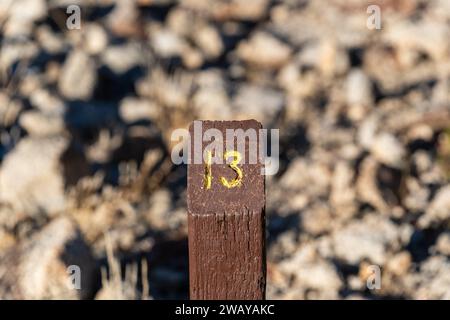 Trail Mile Marker numéro trois (3) sculpté sur un poteau en bois et peint en jaune Banque D'Images