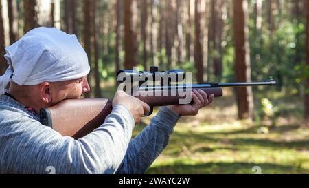 Concept de tir, chasse gros plan. Un homme tire d'une arme pneumatique dans la nature en gros plan. Pièces de fusil à air comprimé et espace de copie. Banque D'Images