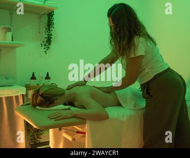 Femme recevant une séance de massage aux mains d'une femme de massage Banque D'Images