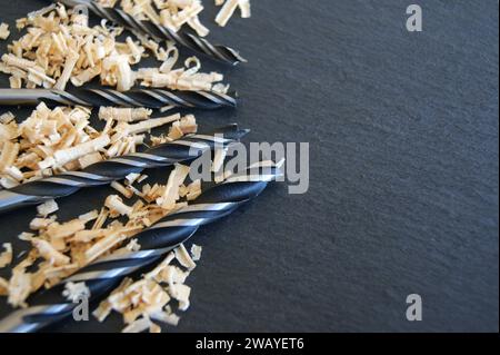 Perceuses pour le forage du bois. Nouveaux forets avec des copeaux de bois sur un fond sombre. Banque D'Images