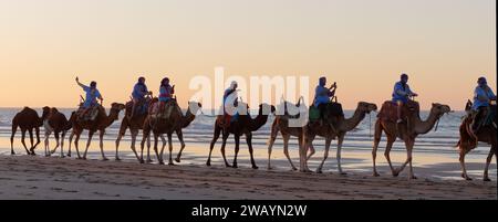 Touriste chameau riders prenant des selfies sur une plage de sable fin lors d'une soirée d'hiver à Essaouira, Maroc, le 7 janvier 2024 Banque D'Images