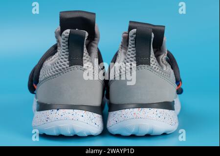 Kid gris chaussures de course vue arrière isolé sur fond de studio bleu Banque D'Images Kid gris chaussures de course vue arrière isolé sur fond de studio bleu Banque D'Images