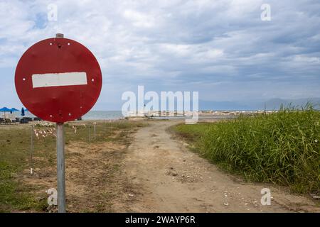 Ancien panneau de trafic sans entrée au premier plan.Bord de mer de la mer Ionienne avec une route de sable et l'herbe verte d'un champ.Ciel nuageux.Roda, CORF Banque D'Images