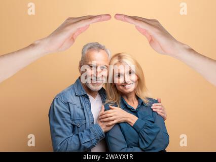 Heureux marié couple mature posant sous le toit sur fond beige Banque D'Images