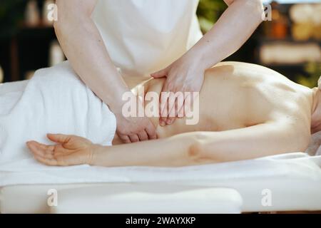 Le temps des soins de santé. Gros plan sur le thérapeute de massage médical dans le salon de spa faire une thérapie de massage sur la table de massage. Banque D'Images