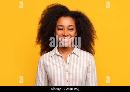 Heureuse dame afro-américaine souriant sur fond jaune Banque D'Images