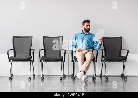 Homme indien examinant des documents dans un environnement de salle d'attente clairsemée Banque D'Images