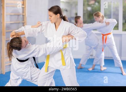 Cours de judo ou de jiu jitsu par paires - deux adolescentes s'entraînent à saisir et à lancer des tapis de sport Banque D'Images