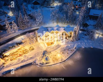 Vue aérienne de maisons illuminées dans un village enneigé la nuit Banque D'Images