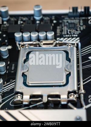 Vue rapprochée d'un socket CPU avec processeur installé sur une carte mère noire, industrie électronique semi-conductrice, carte de circuit imprimé, ordinateur scien Banque D'Images
