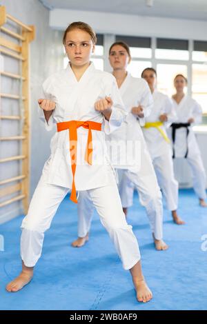 Karatéka adolescent pratiquant les coups de poing pendant le kata à l'entraînement de groupe Banque D'Images