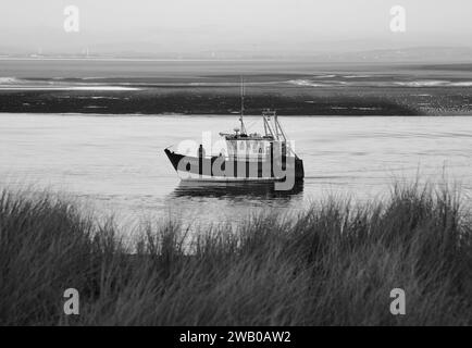 Un bateau de pêche solitaire sur la rivière Wyre à Fleetwood, Lancashire, Royaume-Uni, Europe le samedi 6, janvier 2024 Banque D'Images