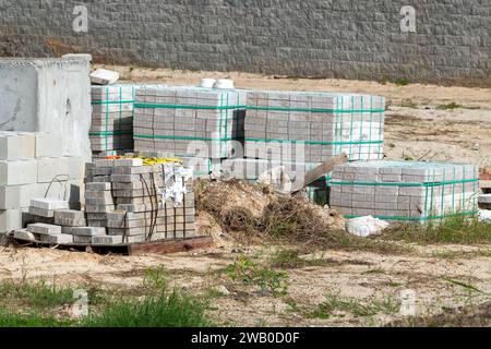 Palettes ou patins en bois de blocs carrés de couleur grise ou de pierres de maçonnerie. Certains sont lâches, et d'autres sont stockés pour les chantiers de construction. Banque D'Images