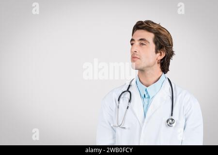 Médecin caucasien réfléchi en manteau blanc avec stéthoscope Banque D'Images