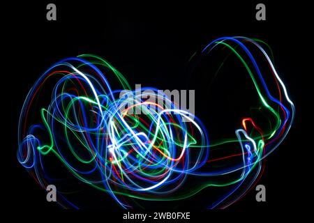 Des traînées de néon et des tourbillons de lumière colorée sur fond noir. Banque D'Images