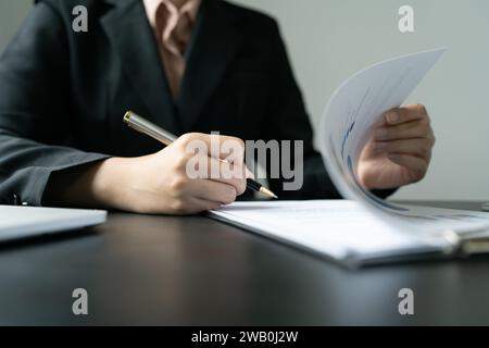 Femme d'affaires signant un document pour approbation avec partenaire dans un dossier Banque D'Images