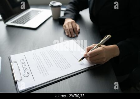 Femme d'affaires signant un document pour approbation avec partenaire dans un dossier Banque D'Images