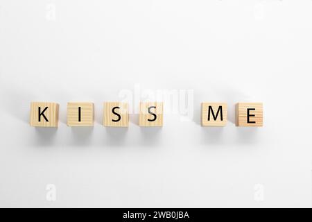 Cubes en bois avec phrase Kiss Me sur fond blanc, plat lay Banque D'Images