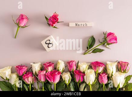 Beau fond festif pour la Journée internationale de la femme le 8 mars avec de délicates roses et blanches et un calendrier en bois. bordure Banque D'Images