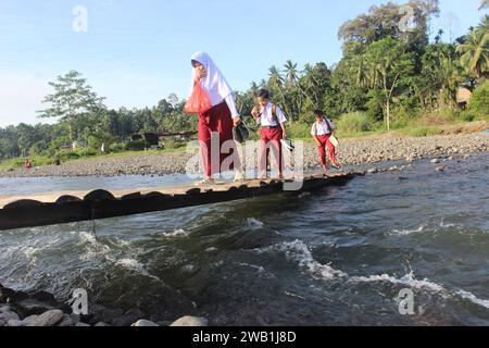 Portrait d'élèves en Indonésie marchant un kilomètre pour se rendre à l'école, traversant une rivière dans le district de Sungai Limau, dans la régence de Padang Pariaman, province de Sumatra Ouest, le 8 janvier 2024. Le gouvernement indonésien a alloué un budget à l'éducation de 660,8 milliards de rands, soit 20 pour cent dans le budget de l'État de 2024, a déclaré ISA Rachmatarwata, directrice générale du budget du ministère indonésien des Finances, le 11 octobre 2023. Banque D'Images