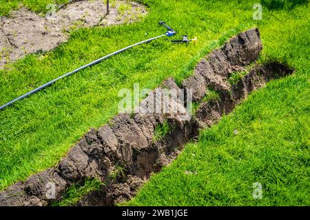 Auto-installation de l'irrigation avec un arroseur rétractable dans la pelouse finie. Pose de conduites d'eau avec des pulvérisateurs sous la pelouse pour l'irrigation. Banque D'Images