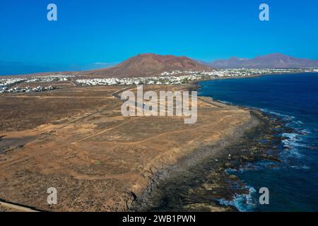 Côte de Playa Blanca. Vue panoramique drone aérien avec volcan rouge en arrière-plan. Tourisme et concept de vacances. Flamingo Beach Lanzarote, Canar Banque D'Images