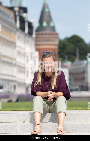 Femme suédoise assise sur les marches à Angfaerjepark au Kajpromenaden, portrait, derrière la mairie, Helsingborg, province Skane laen, Suède Banque D'Images