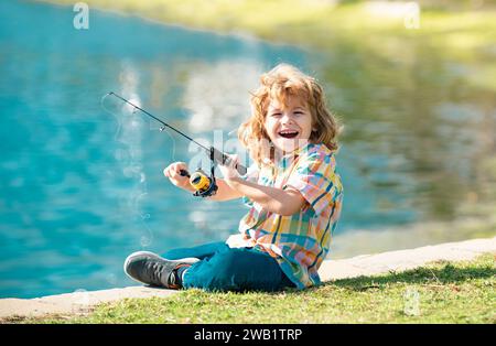 Drôle de pêche de petit enfant heureux le week-end. Un garçon de pêcheur se tient dans le lac avec une canne à pêche et attrape du poisson. Banque D'Images