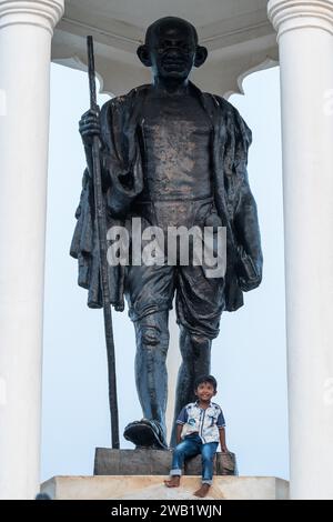 Child at the foot of a Mahatma Gandhi monument, statue, former French colony of Pondicherry or Puducherry, Tamil Nadu, India Stock Photo