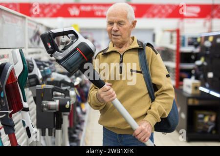 Senor homme retraité achetant aspirateur droit dans la salle d'exposition du magasin d'appareils électriques Banque D'Images