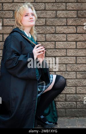 Une cosplayeuse blonde caucasienne habillée comme un sorcier avec une baguette magique Banque D'Images