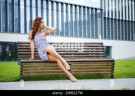 Belle femme s'assied sur le banc en robe de chambre et regardant loin Banque D'Images