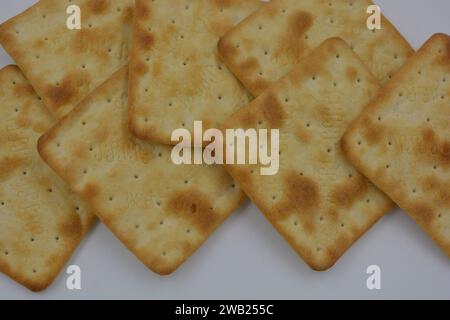 Biscuits de marque, fabriqués en usine, de grands crackers salés minces sont disposés sur un fond blanc. Banque D'Images