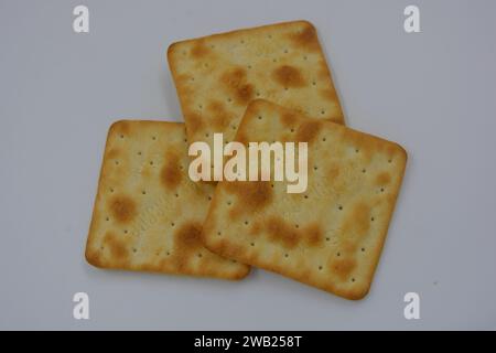 Biscuits de marque, fabriqués en usine, de grands crackers salés minces sont disposés sur un fond blanc. Banque D'Images