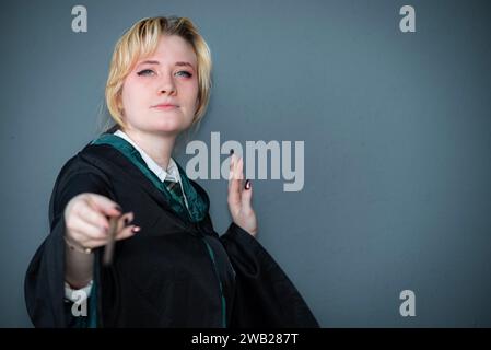 Une cosplayeuse blonde caucasienne habillée comme un sorcier avec une baguette magique Banque D'Images