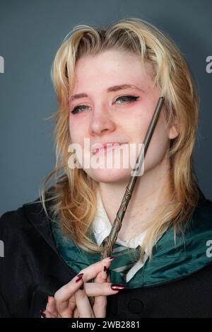 Une cosplayeuse blonde caucasienne habillée comme un sorcier avec une baguette magique Banque D'Images