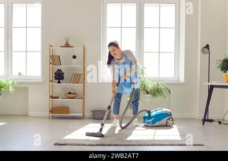Femme passant l'aspirateur sur le tapis du salon Banque D'Images