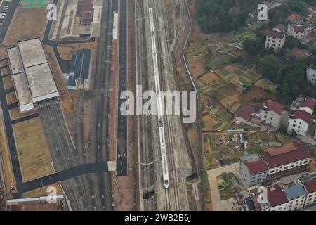 Shaoxing. 8 janvier 2024. Cette photo aérienne prise le 8 janvier 2024 montre un train au départ de la gare de Xinchang à Shengzhou, dans la province du Zhejiang dans l'est de la Chine. Le chemin de fer interurbain Hangzhou-Shaoxing-Taizhou, le premier chemin de fer à grande vitesse de Chine contrôlé par des capitaux privés, a célébré lundi son 2e anniversaire de fonctionnement. Avec une vitesse nominale de 350 kilomètres à l'heure, le chemin de fer a livré un total de 20 millions de passagers depuis sa mise en service. Crédit : Huang Zongzhi/Xinhua/Alamy Live News Banque D'Images