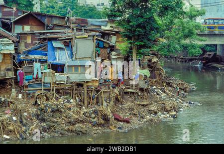 Indonésie, Jakarta. Famille devant leur cabane dans un bidonville à côté d'une rivière polluée. Banque D'Images