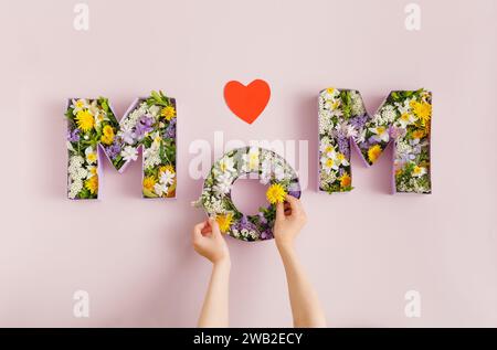 Boîtes en forme de MOM Word pleines de fleurs. Concept de fête des mères Banque D'Images
