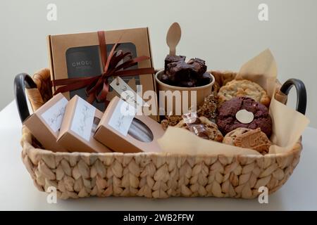 Panier Whicker rempli de friandises cuites sur une table blanche Banque D'Images